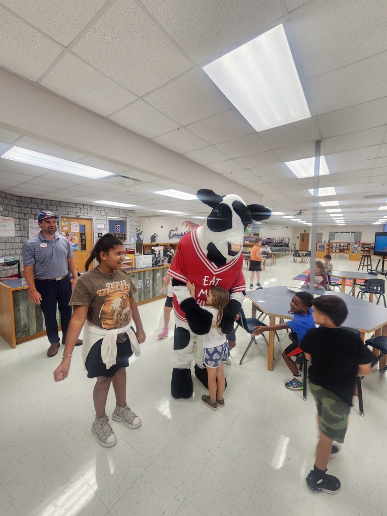 Chick Fil A cow visiting MES daycare as part of the company Million Book give away. Students and cow present in the pictures.