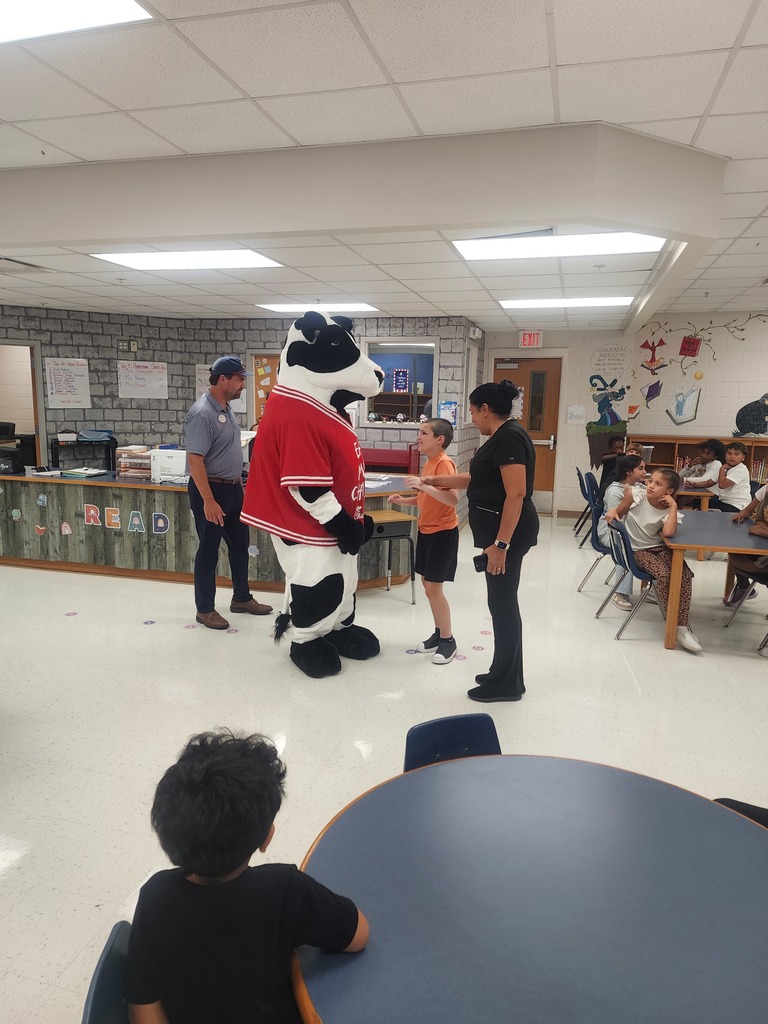 Chick Fil A cow visiting MES daycare as part of the company Million Book give away. Students and cow present in the pictures.