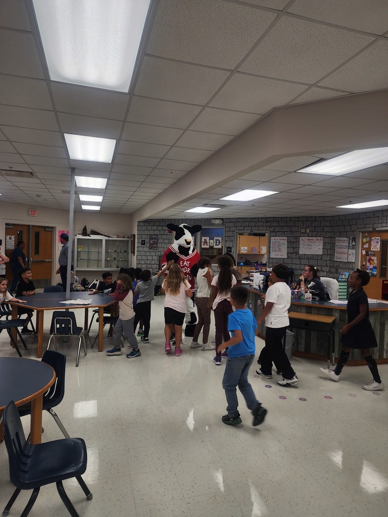 Chick Fil A cow visiting MES daycare as part of the company Million Book give away. Students and cow present in the pictures.