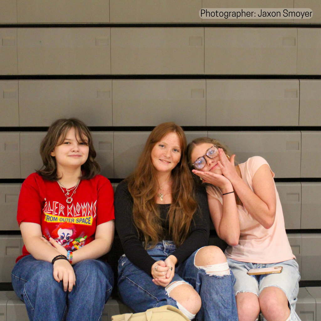 Three students seated in gym. 