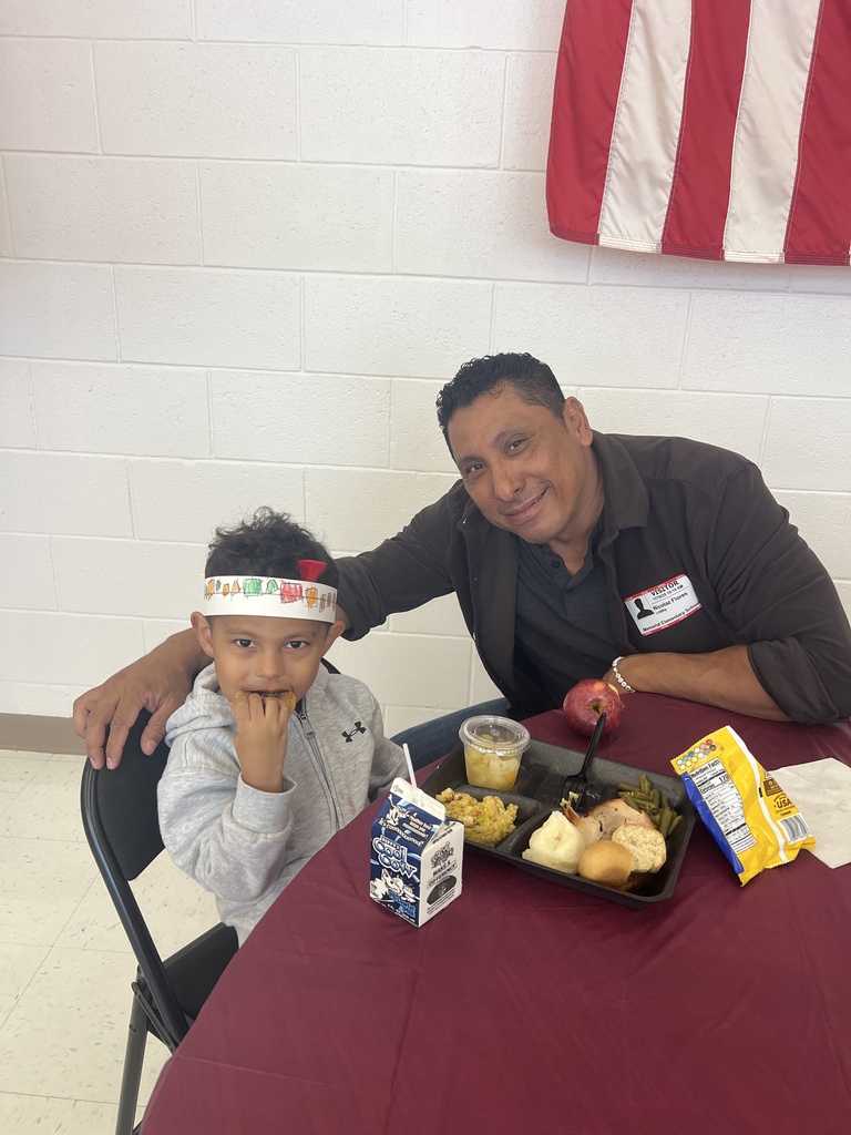 MES families enjoying Thanksgiving lunch with their child.
