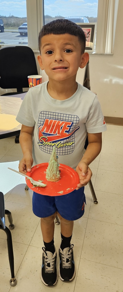 MES kinder student holding their 3D cone decorated as a Christmas tree.