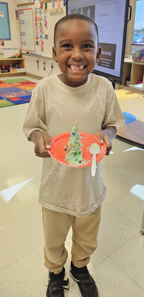 MES kinder student holding their 3D cone decorated as a Christmas tree.