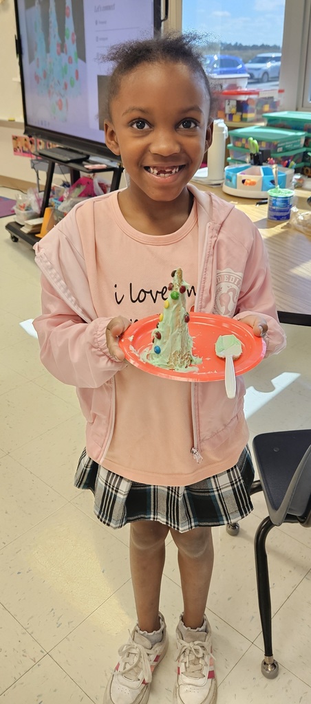 MES kinder student holding their 3D cone decorated as a Christmas tree.