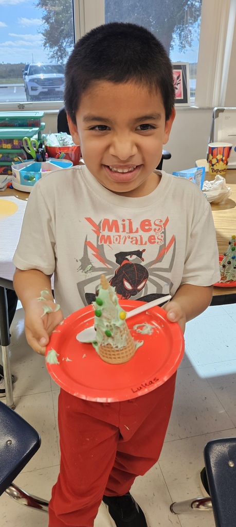 MES kinder student holding their 3D cone decorated as a Christmas tree.