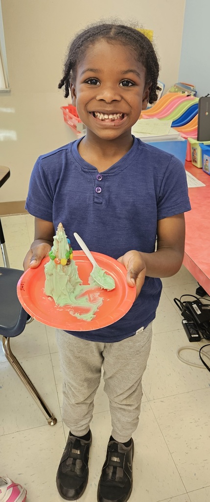 MES kinder student holding their 3D cone decorated as a Christmas tree.