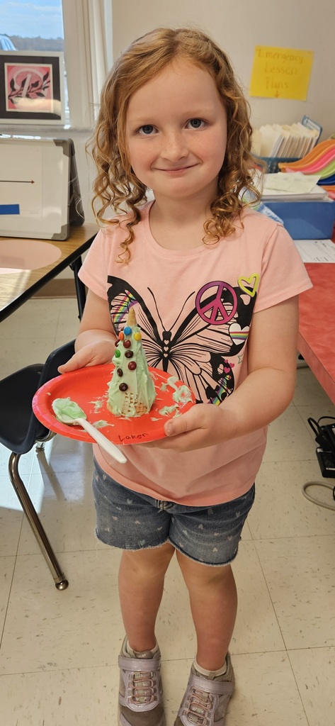 MES kinder student holding their 3D cone decorated as a Christmas tree.