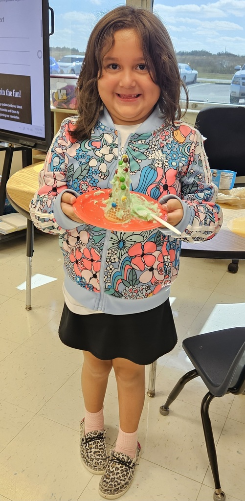 MES kinder student holding their 3D cone decorated as a Christmas tree.