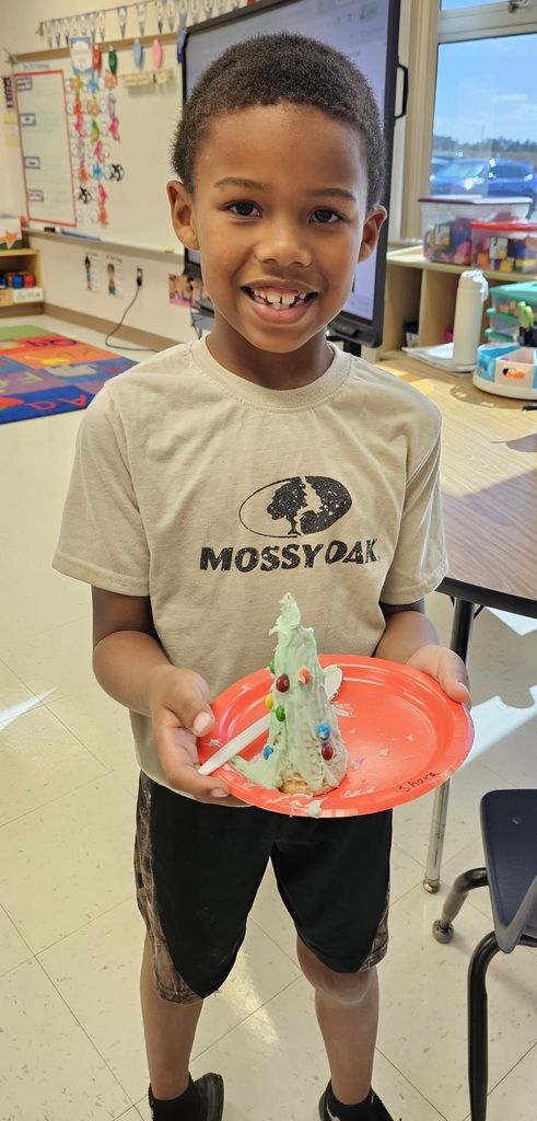 MES kinder student holding their 3D cone decorated as a Christmas tree.