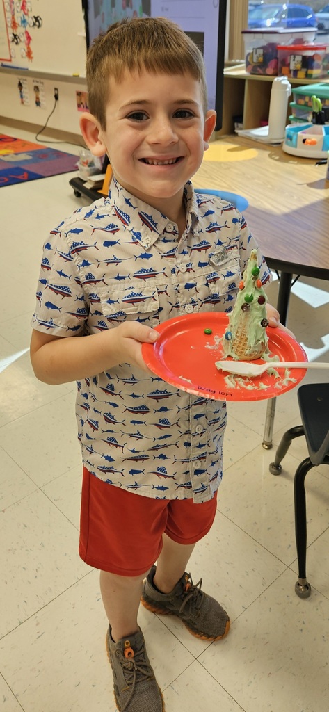 MES kinder student holding their 3D cone decorated as a Christmas tree.