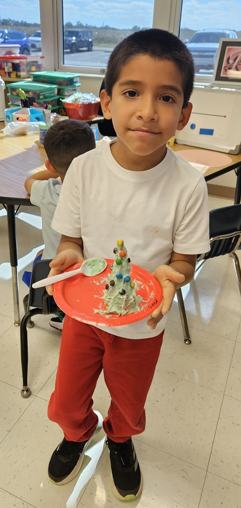 MES kinder student holding their 3D cone decorated as a Christmas tree.