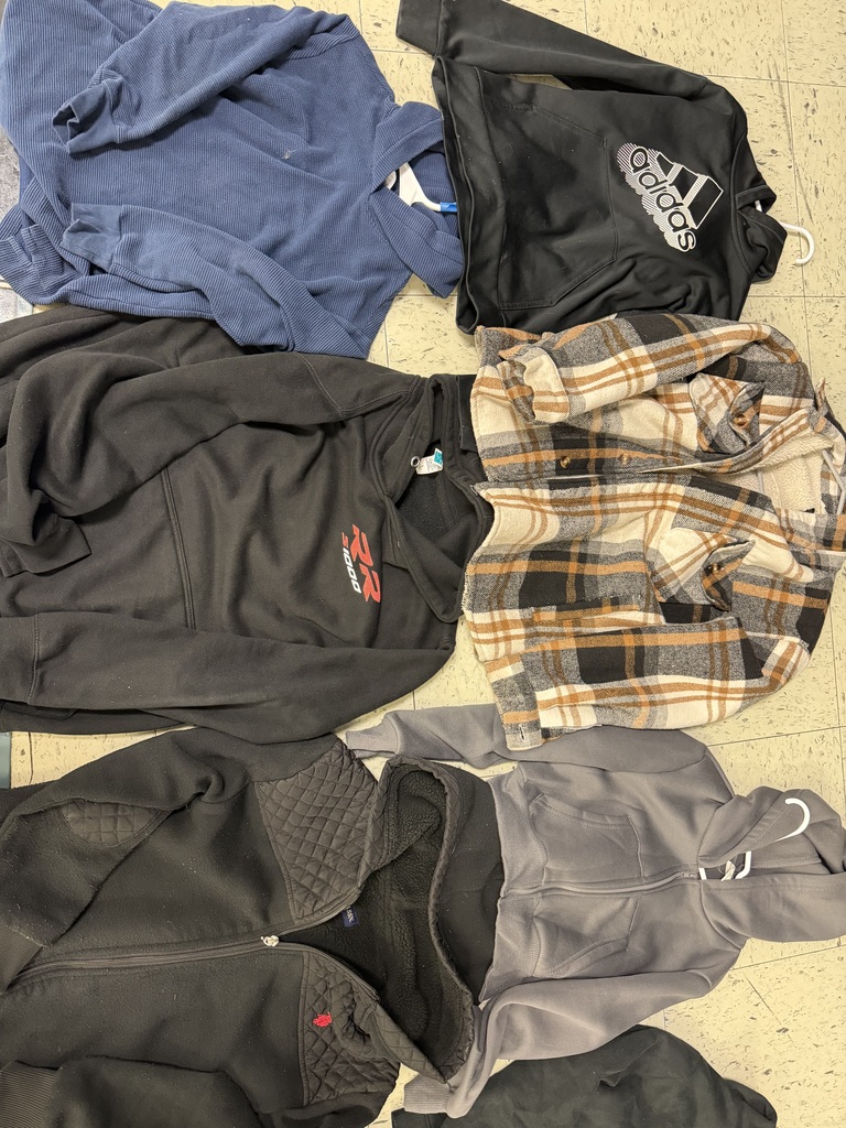 Five jackets and hoodies on a tile floor, including a blue corduroy hoodie, a black Adidas hoodie, a black "RR 1000" hoodie, a brown plaid flannel, and two zip-up jackets in black and gray.