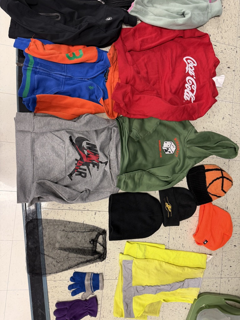 An assortment containing a Nike Air hoodie, a green Minecraft hoodie, a Coca-Cola sweatshirt, several beanies (including a basketball-themed one), gloves, and a yellow safety vest spread across a floor.