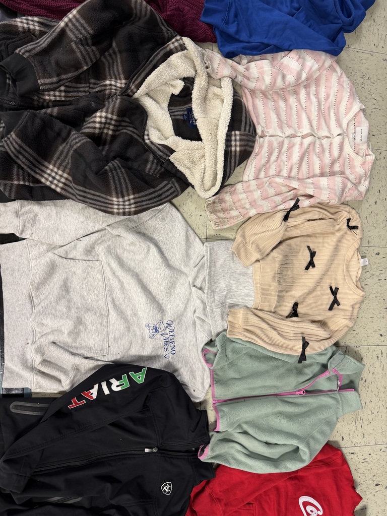 A collection of outerwear including a sherpa-lined plaid jacket, a white "Weekend Vibes" hoodie, a cream sweater with black bows, a pink striped cardigan, a black Ariat jacket, and a mint green fleece.