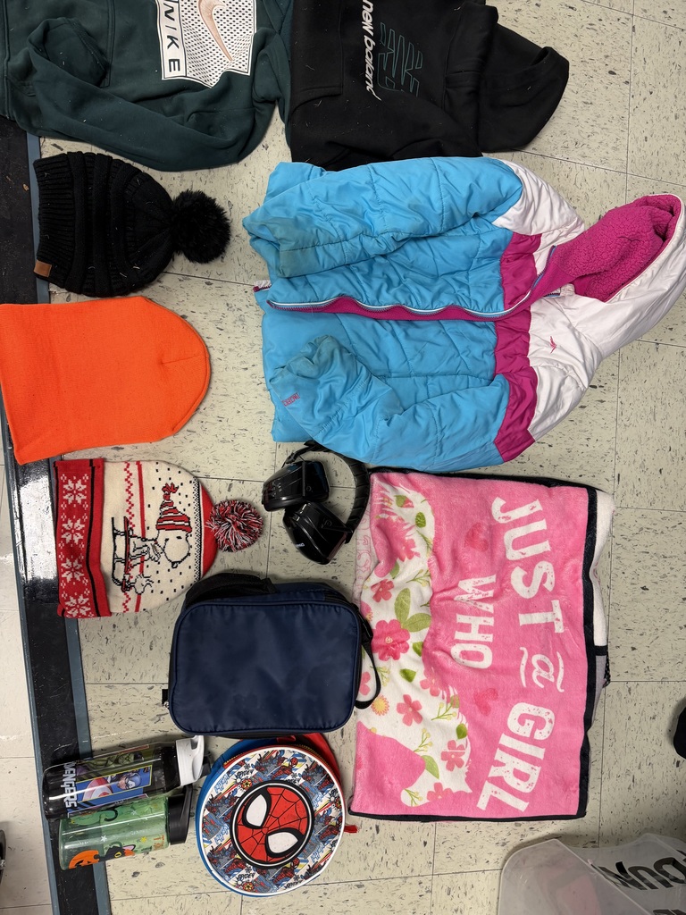 A collection of accessories including three beanies (black, orange, and a Snoopy holiday theme), a blue lunchbox, a Spider-Man case, two water bottles, black earmuffs, a pink "Just a Girl Who..." blanket, and a puffer jacket.