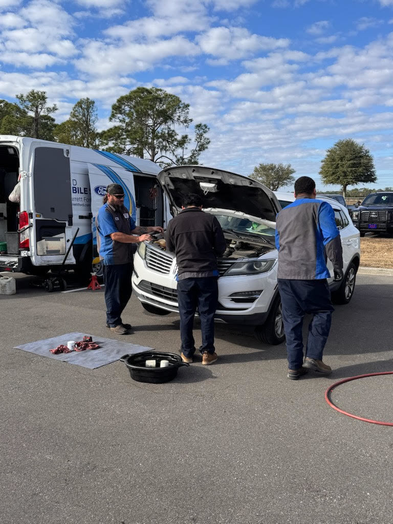 Hard working crew from Bill Jarrett Ford's mobile oil unit changing staff member's oil.