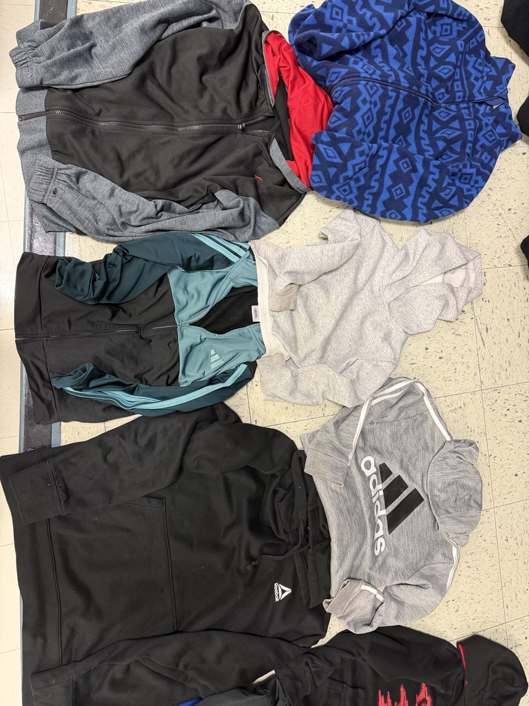A collection of five hoodies and jackets on a tile floor. Includes a blue patterned fleece, a grey and black zip-up, a teal-accented Adidas jacket, a grey Adidas hoodie, and a solid black Reebok hoodie.