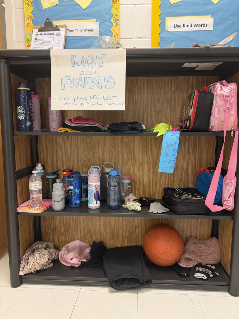 A three-tier wooden "Lost and Found" shelf. The top shelf holds water bottles and lunch boxes; the middle shelf is crowded with various colorful water bottles, including an "Elsa" bottle; the bottom shelf contains a basketball, scarves, a pink bonnet, and stray gloves.