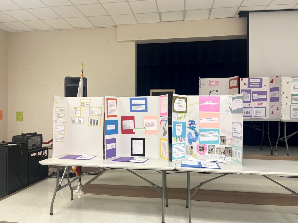 5th grade science projects on display on tables in the cafeteria.