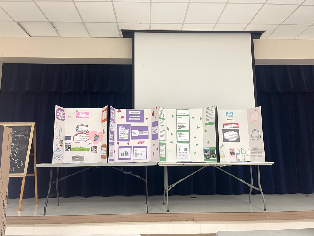 5th grade science projects on display on tables in the cafeteria.