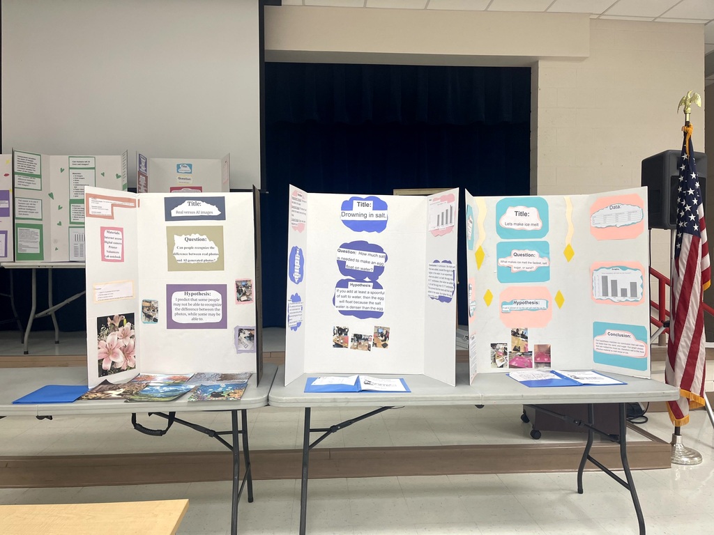 5th grade science projects on display on tables in the cafeteria.