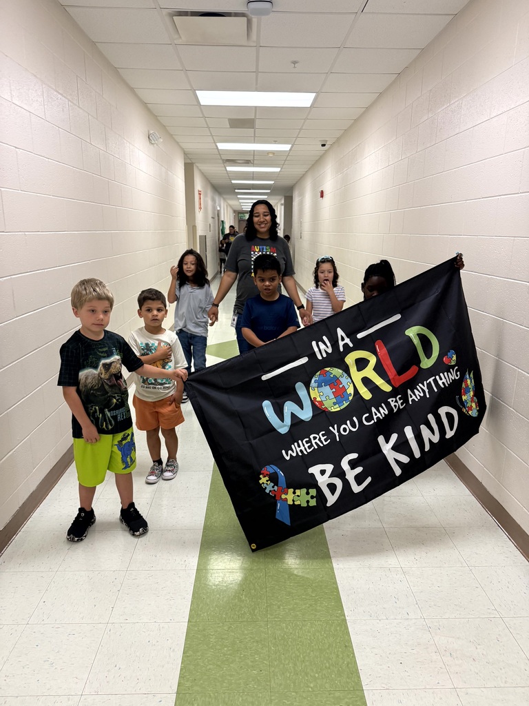 Students walking the hall, banner says In a World where you can be anything Be Kind.