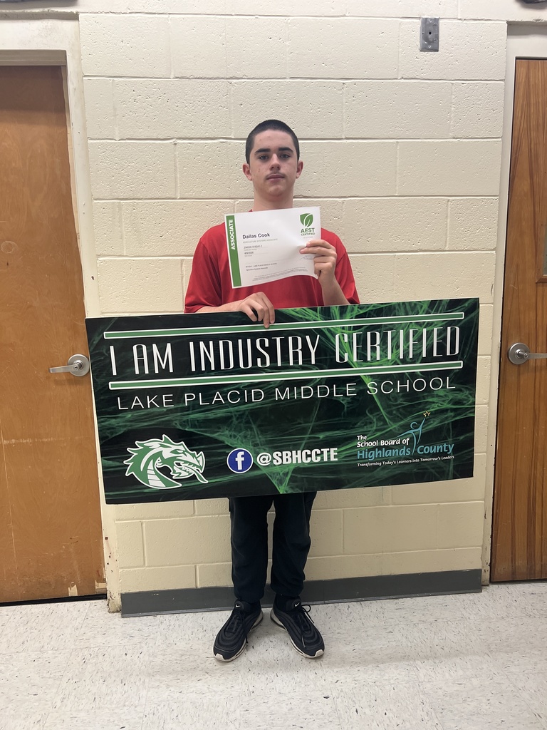 Dallas Cook showing he is Industry Certified at Lake Placid Middle. Student is holding his certificate and the large sign. 