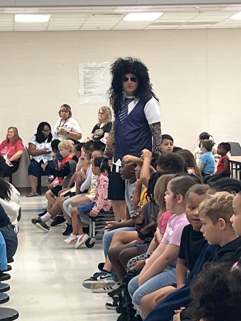 Mr. Taylor at the pep rally. Students seated at tables. 
