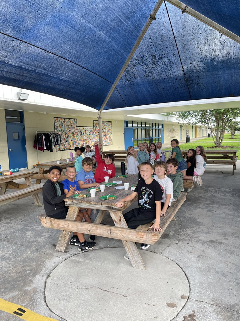students eating pancakes and sitting at a picnic table smiling