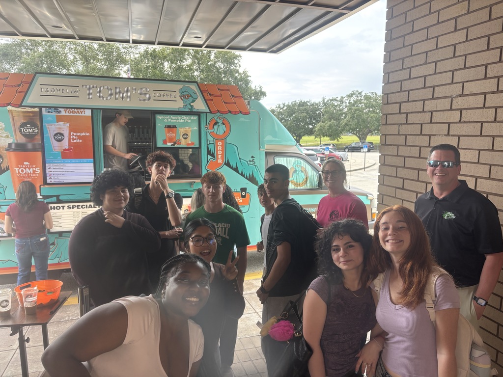 Students and staff pose together outside in front of a Travelin' Tom's Coffee Truck.   