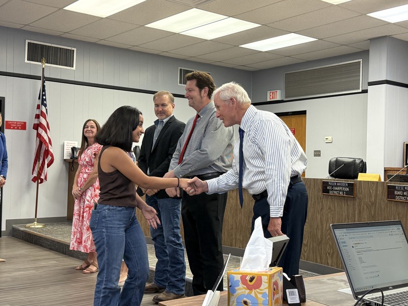 Board member Mason Whiden shaking hands with recipient, Laura Vega