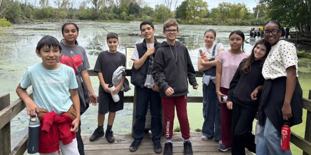 students on a dock by a pond in a forest preserve