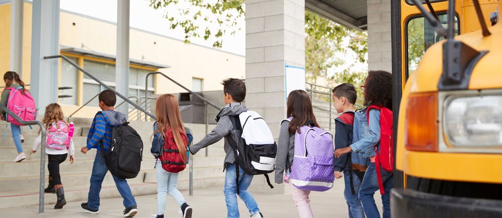 Students exiting a bus and into a school