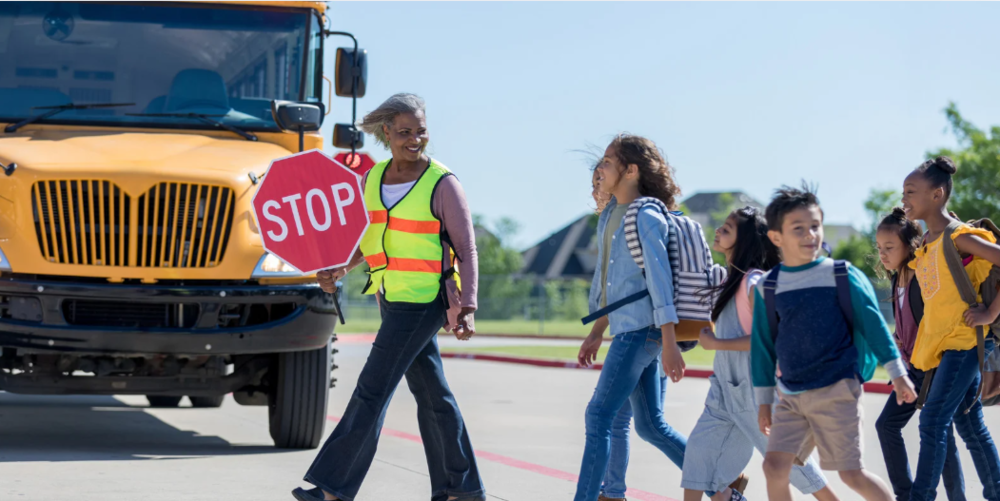crossing guard crossing students in front of school bus