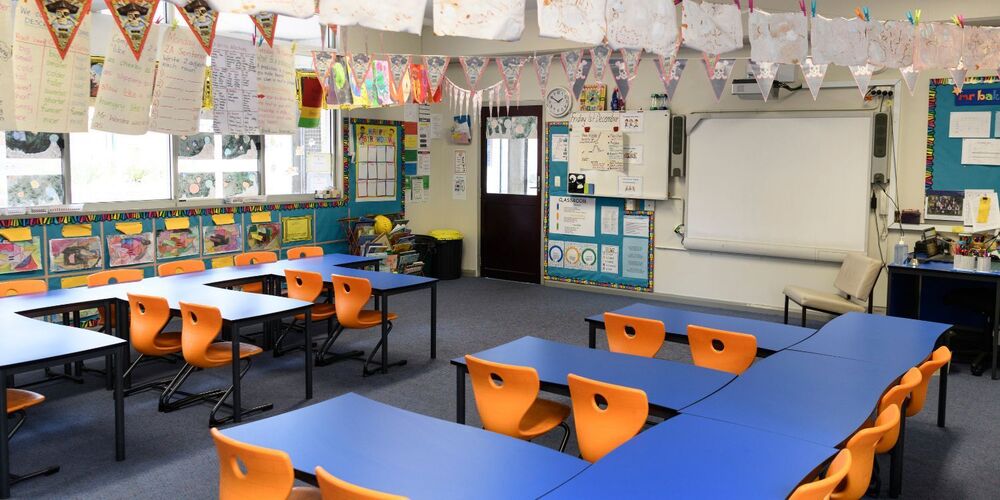 School classroom with blue tables and orange seats