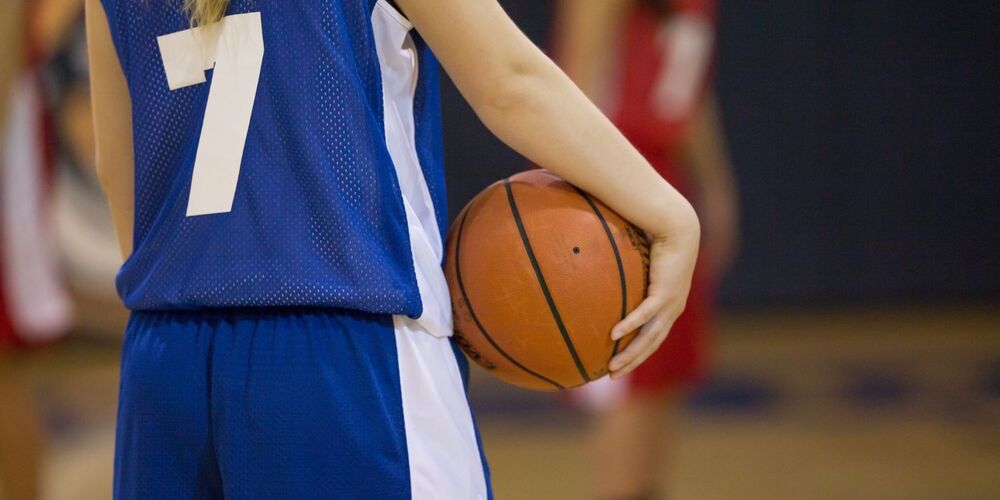 Girl in basketball uniform holding basketball