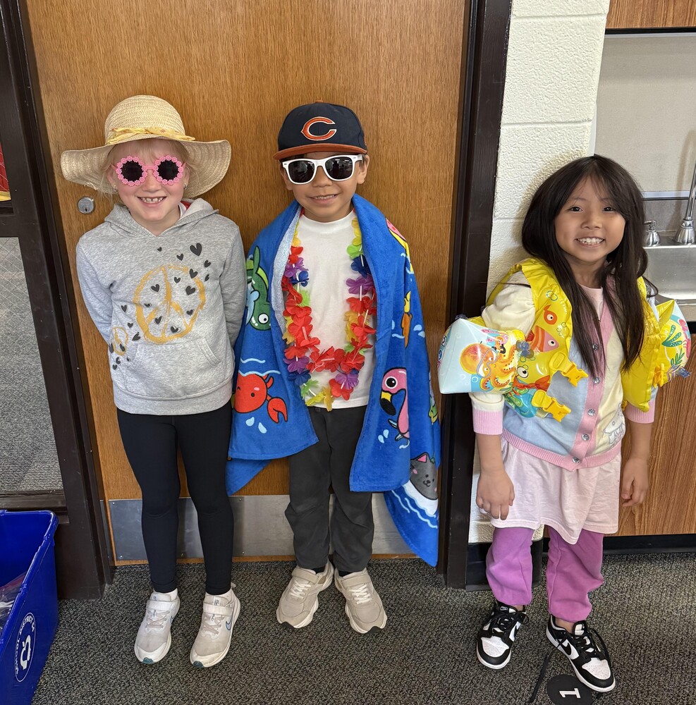 Students wearing summer gear like sunglasses, hats, towels, and swim floaties