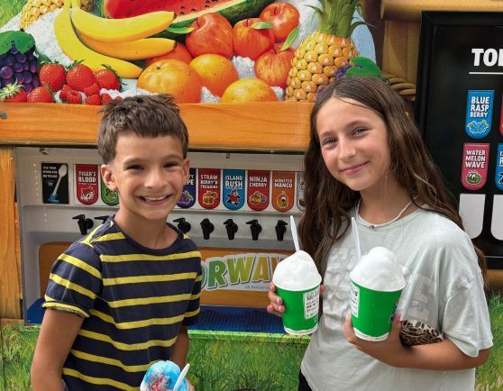Two kids in front of a Kona Ice truck