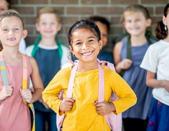 A student smiling with other kids in the background.