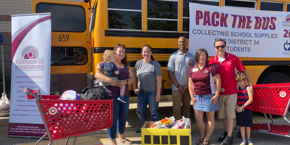 Volunteers standing in front of school bus with school supplies