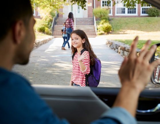 Dad in a car waving to a child walking