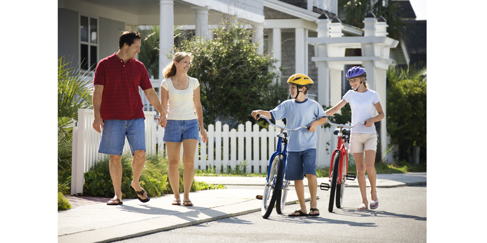 photo of two adults walking and two kids walking bikes