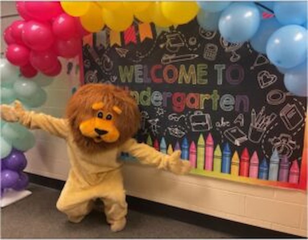 Lazlo the Lion in front of Welcome to Kindergarten sign