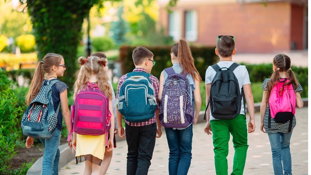 A line of 6 kids walking up to school