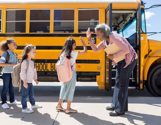 Kids walking on to a bus high fiving the driver