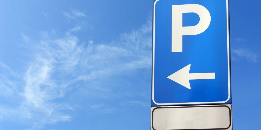Blue sign with the letter P and an arrow pointing left with a blue sky background