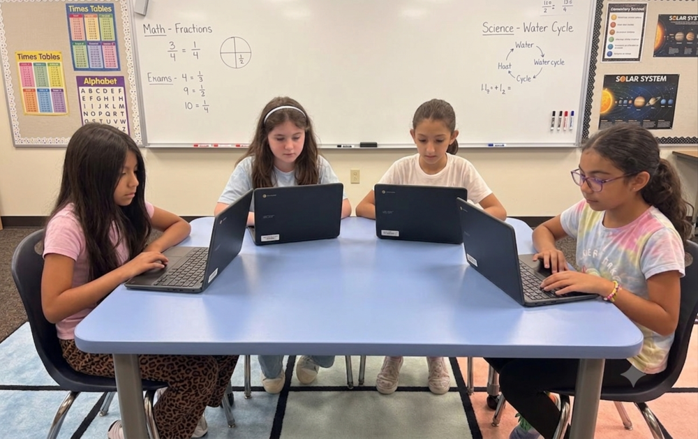 Girls sitting at a table working on chromebooks 