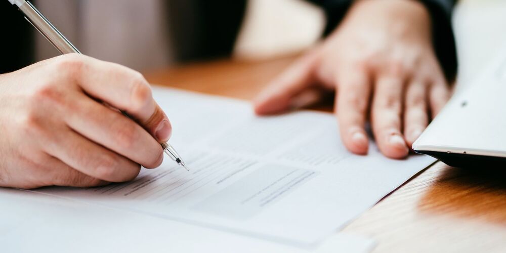 Hand holding pen filling out form