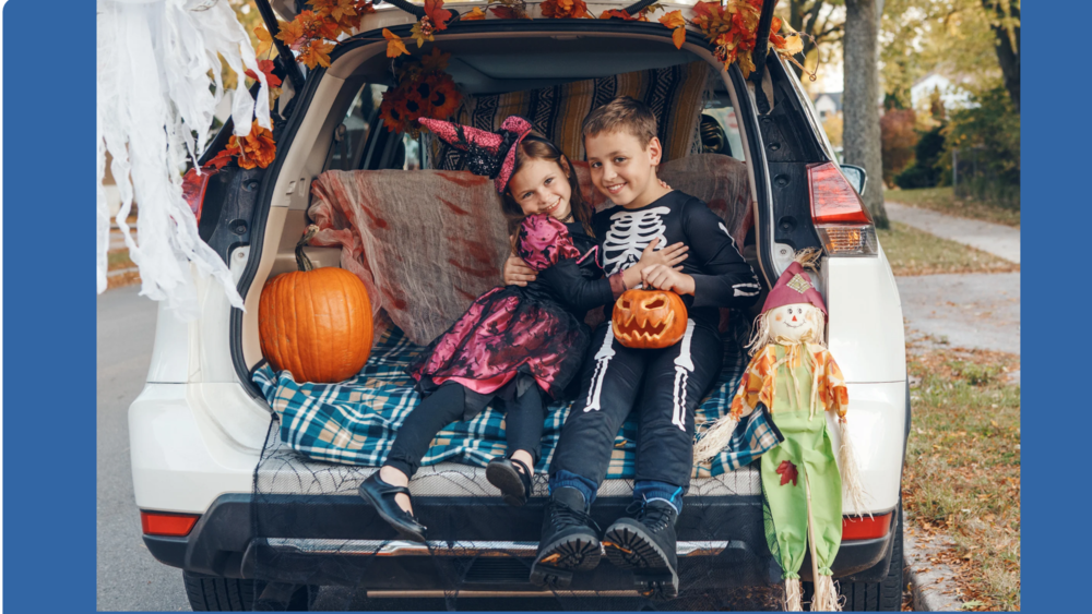Kids sitting in a trunk with their halloween costumes