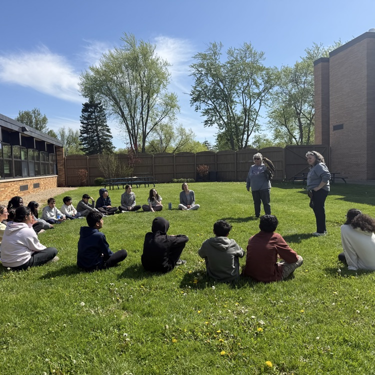 students sitting in a circle looking at a bird of prey